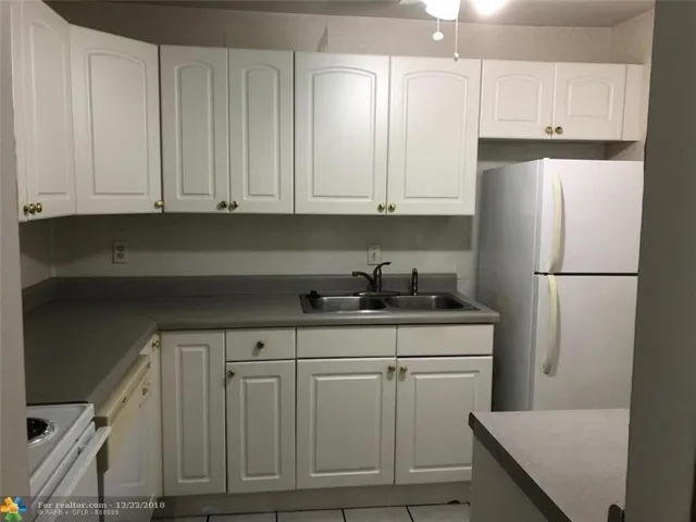 a kitchen with white cabinets and refrigerator