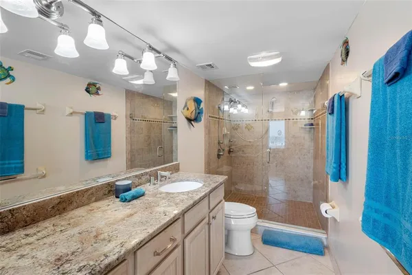 a bathroom with a granite countertop sink a mirror a bathtub and shower