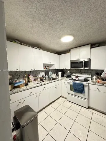 a kitchen with a refrigerator a stove top oven and cabinets