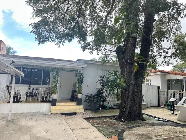 a view of a house with large tree and wooden fence