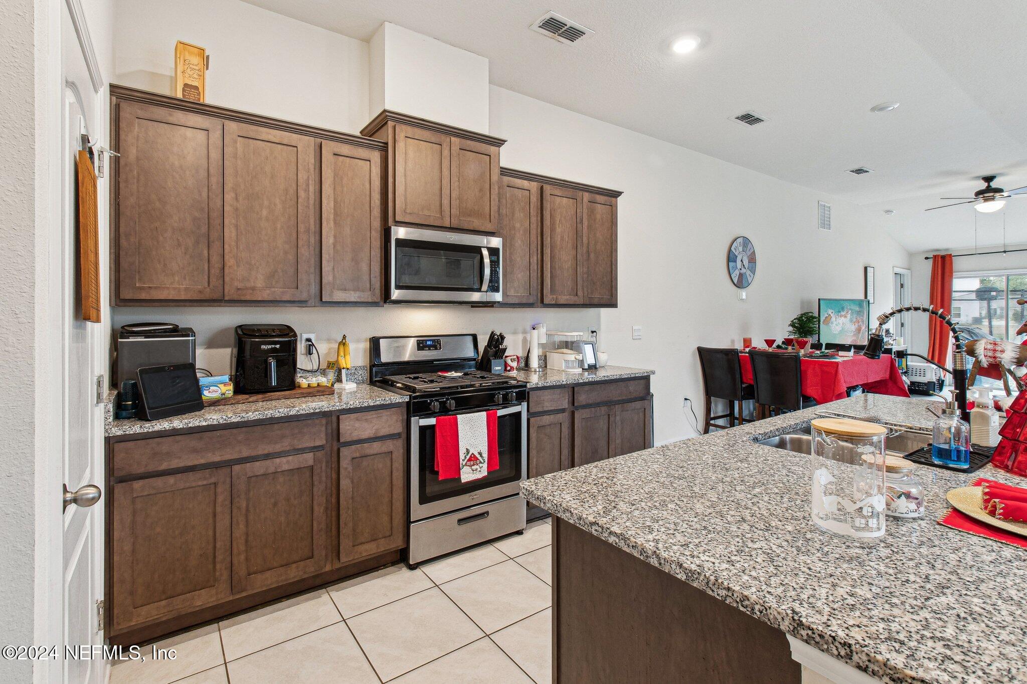 86253 Mainline Road Yulee, FL 32097 - Photo 14 of 39 a kitchen with kitchen island granite countertop a sink dishwasher stove and cabinets