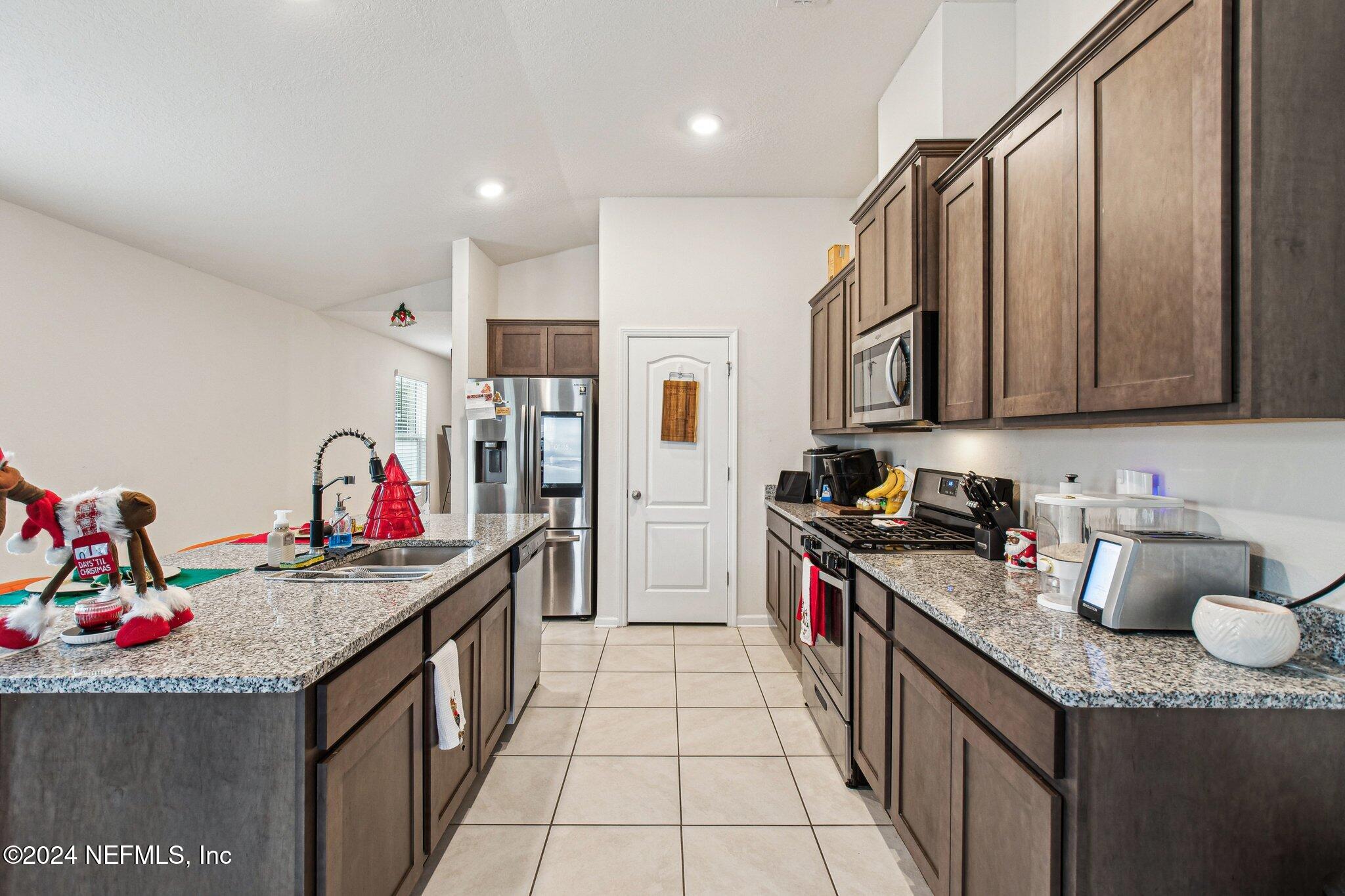 86253 Mainline Road Yulee, FL 32097 - Photo 16 of 39 a kitchen with stainless steel appliances granite countertop a sink stove and refrigerator