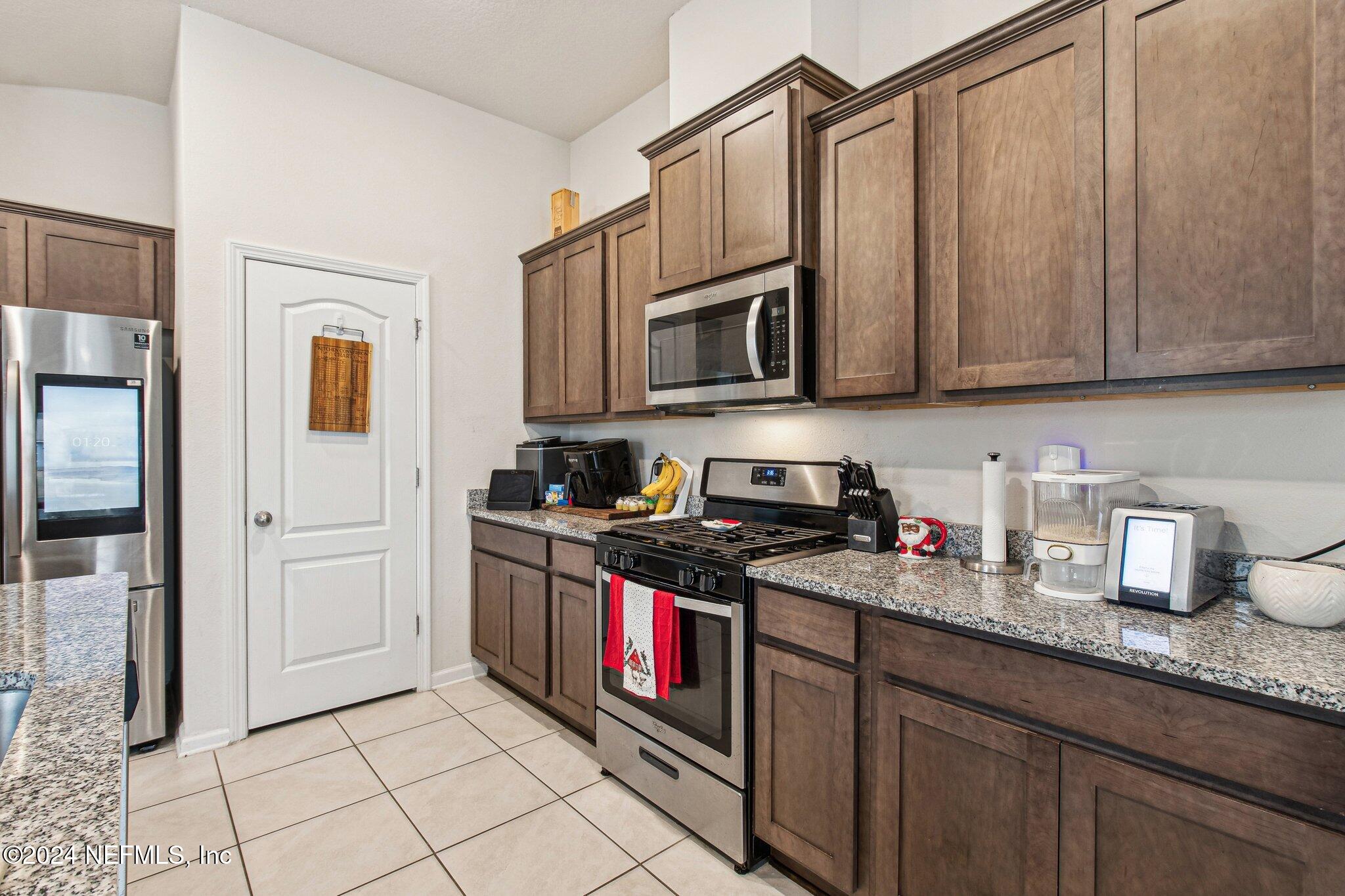 86253 Mainline Road Yulee, FL 32097 - Photo 18 of 39 a kitchen with stainless steel appliances granite countertop a stove a sink and a refrigerator