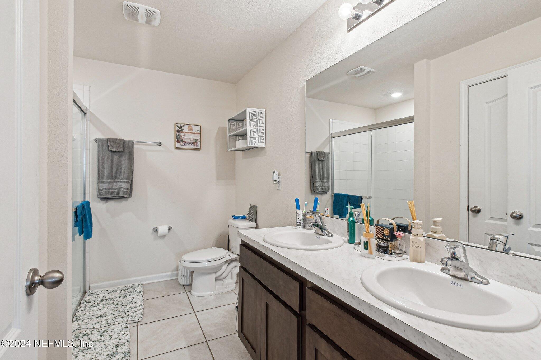 86253 Mainline Road Yulee, FL 32097 - Photo 25 of 39 a bathroom with a double vanity sink toilet and mirror