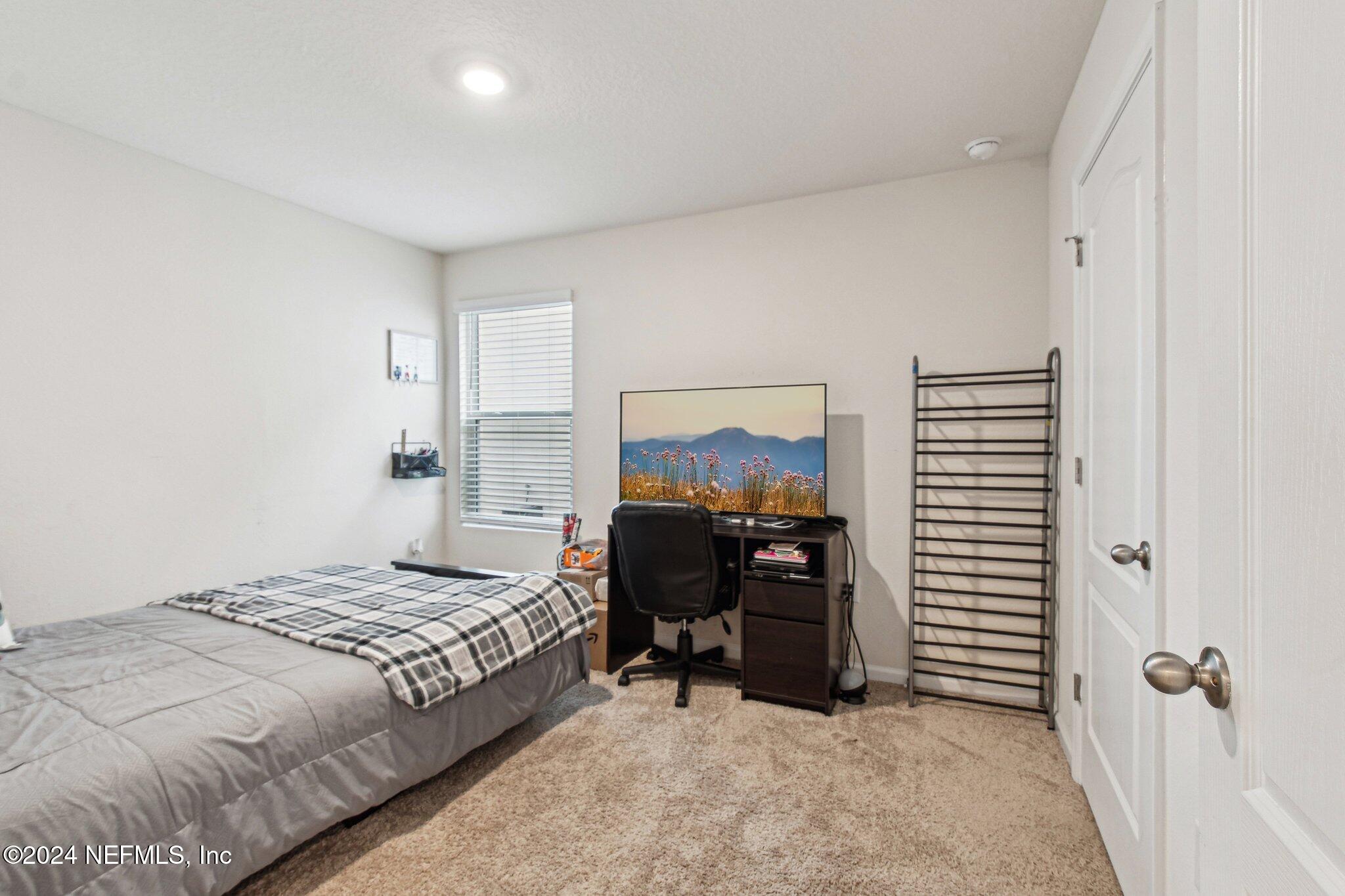 86253 Mainline Road Yulee, FL 32097 - Photo 28 of 39 a bedroom with a bed and a chandelier