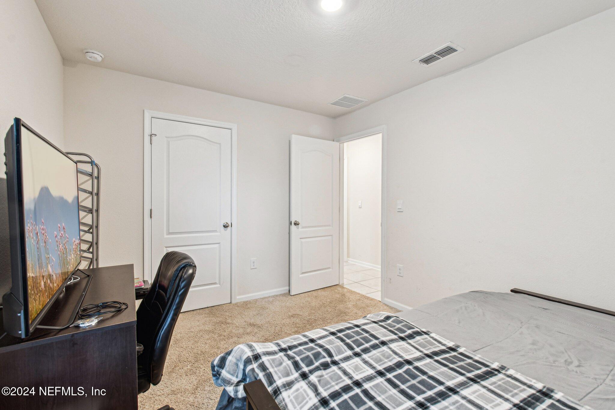 86253 Mainline Road Yulee, FL 32097 - Photo 29 of 39 a bedroom with a bed flat screen tv and a window