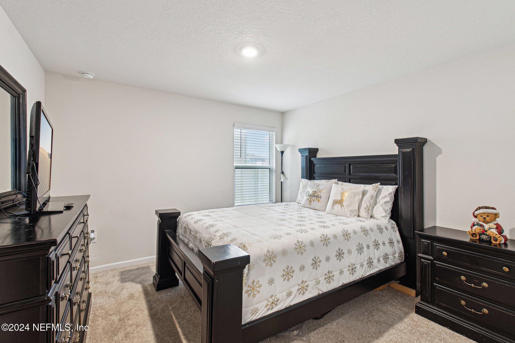 86253 Mainline Road Yulee, FL 32097 - Photo 30 of 39 a bedroom with a bed and a flat tv screen on dresser