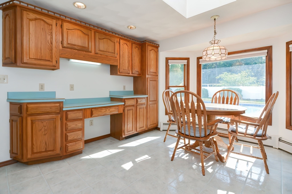 59 Breckenridge Road Tewksbury, MA 01876 - Photo 23 of 42 a kitchen with stainless steel appliances granite countertop a sink a stove a dining table and chairs with wooden floor
