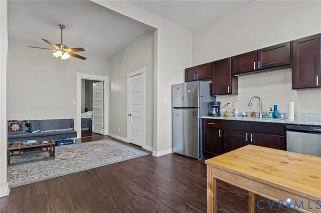 a kitchen with stainless steel appliances granite countertop a refrigerator a sink dishwasher a stove and a dining table with wooden floor