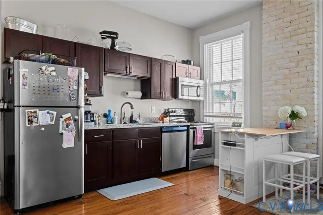 a kitchen with stainless steel appliances granite countertop a refrigerator a sink dishwasher a stove and white countertops with wooden floor