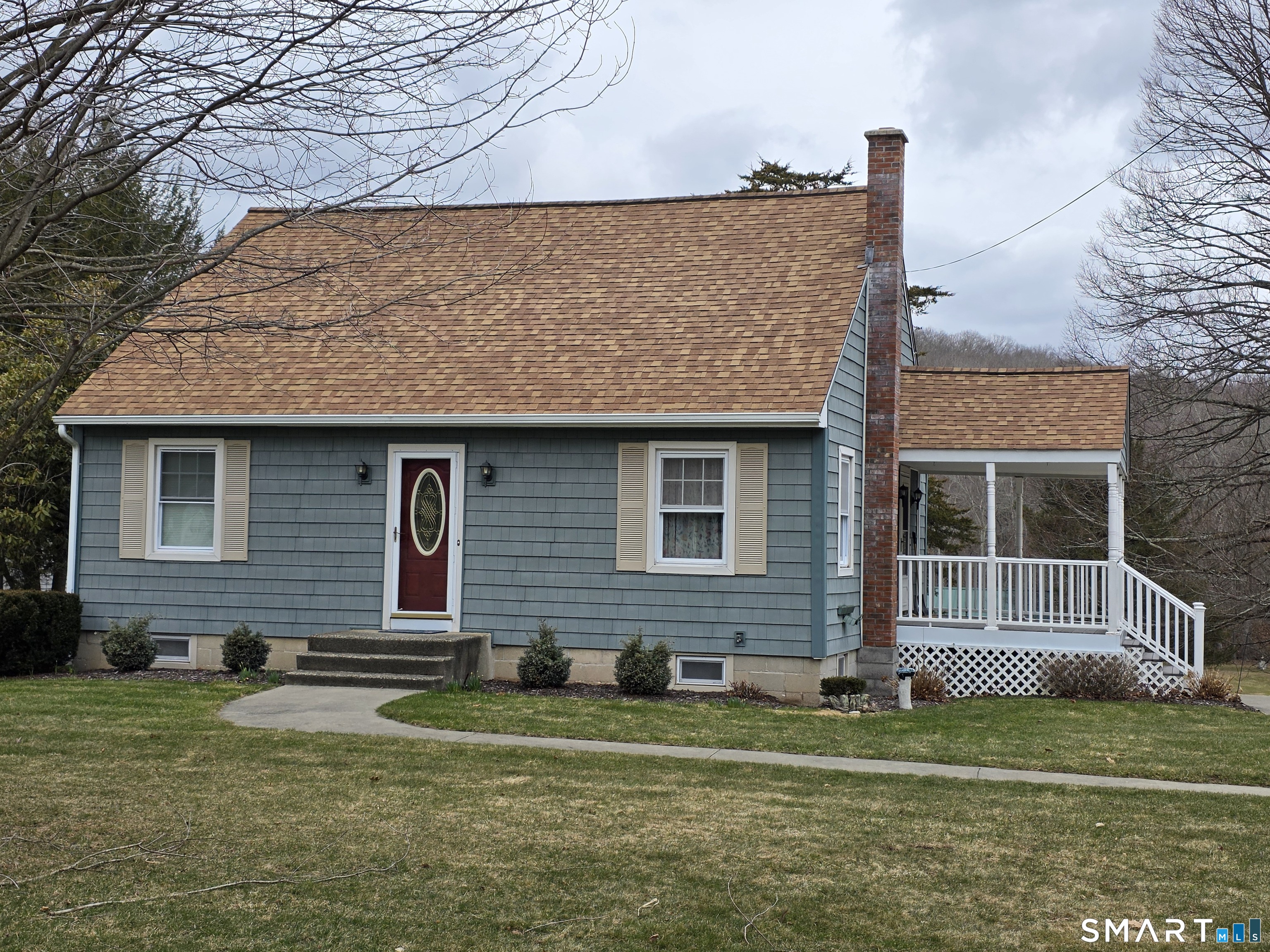 a brick house that has a small yard and large trees