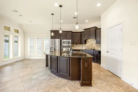 a open kitchen with stainless steel appliances kitchen island granite countertop a refrigerator a oven and a sink