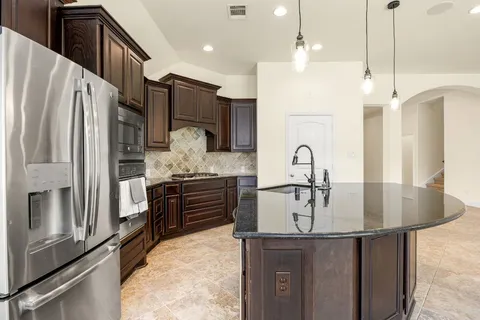 a kitchen with stainless steel appliances granite countertop a sink refrigerator and cabinets