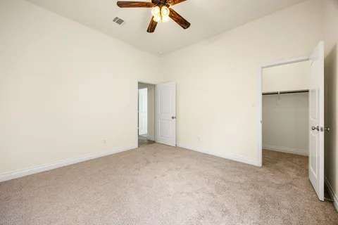 an empty room with a ceiling fan and carpet