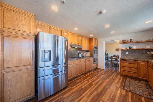 a kitchen with stainless steel appliances granite countertop a refrigerator stove and oven with wooden floor