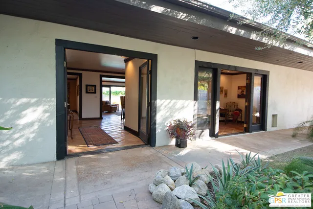 a hallway with wooden floor chandelier and living room