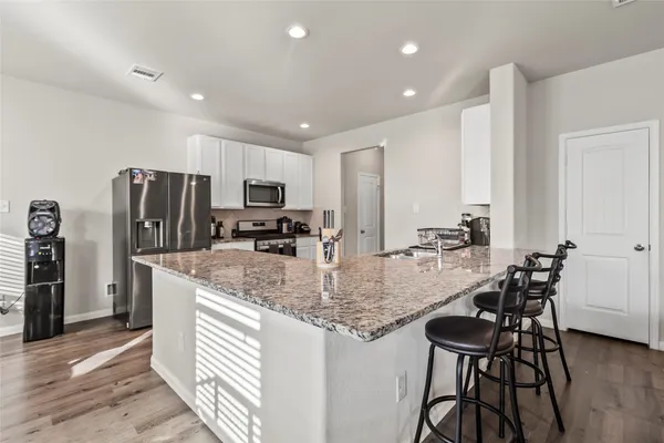 a kitchen with stainless steel appliances granite countertop a table chairs and a refrigerator