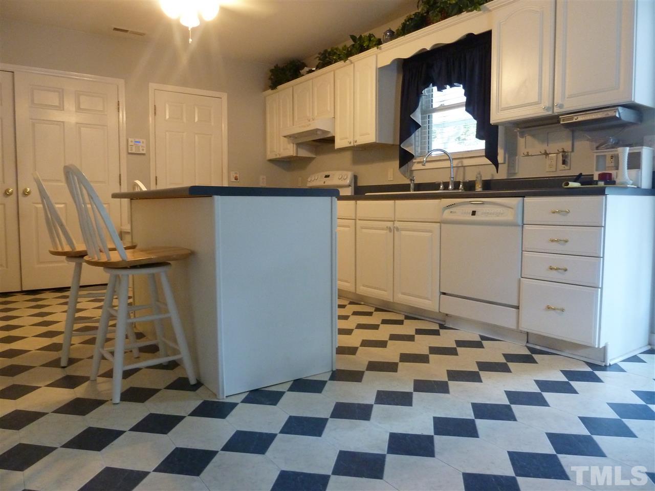 1122 Arvin Road Durham, NC 27704 - Photo 4 of 9 a kitchen with a checkered floor and white cabinets
