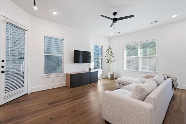 a living room with furniture floor to ceiling window hardwood floor and a flat screen tv