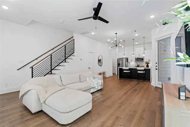 a living room with furniture kitchen view and a wooden floor