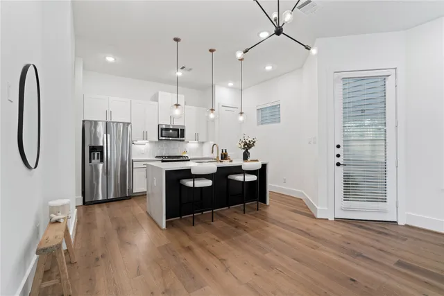 a kitchen with stainless steel appliances a refrigerator sink and wooden floor
