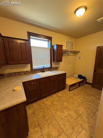 1925 Doe Valley Road Guffey, CO 80820 - Photo 12 of 30 Kitchen featuring dark brown cabinetry, light tile patterned flooring, and light stone counters