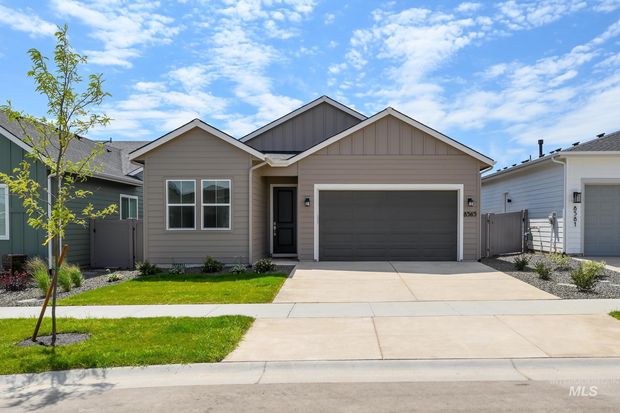 Ranch-style house featuring board and batten siding, an attached garage, concrete driveway, and a gate