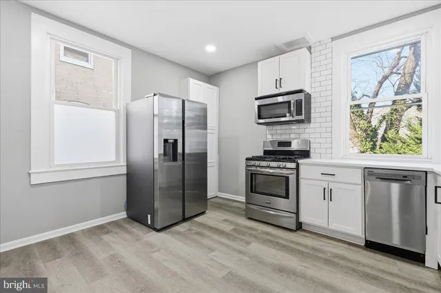 a kitchen with granite countertop a refrigerator and a stove top oven