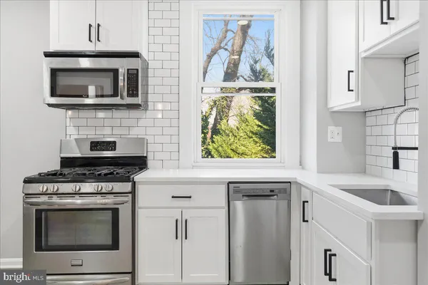 a kitchen with granite countertop a stove top oven microwave and cabinets