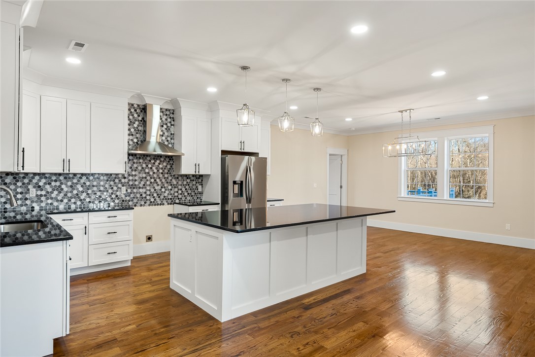 303 Regency Circle Anderson, SC 29625 - Photo 7 of 50 This bright kitchen features sleek black countertops and hardwood floors, offering a contemporary and open feel.