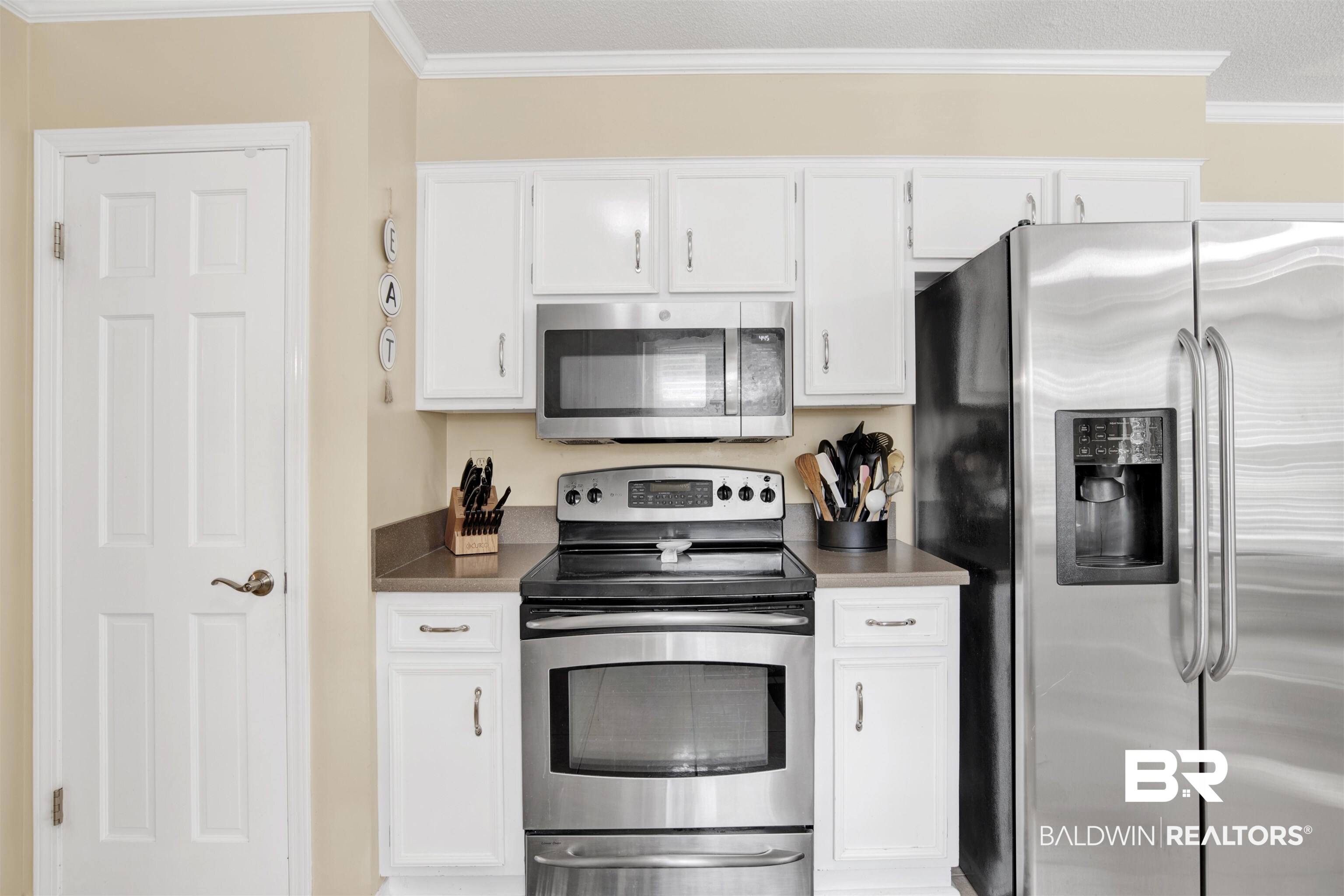 7431 Summer Court Mobile, AL 36695 - Photo 14 of 37 Kitchen with stainless steel appliances, crown molding, white cabinetry, and dark countertops