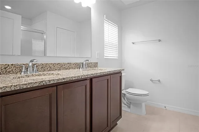 a bathroom with a granite countertop sink and a toilet