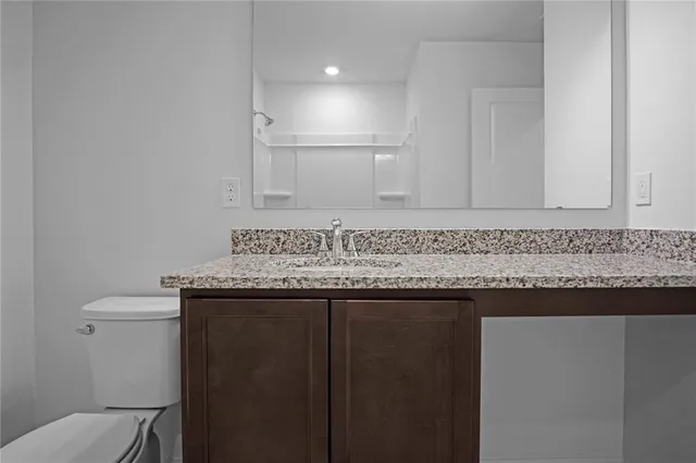 a bathroom with a granite countertop sink and a toilet