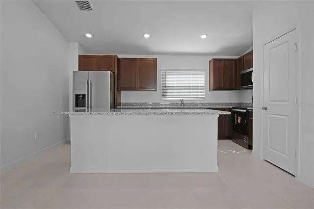 a kitchen with stainless steel appliances granite countertop a refrigerator and a stove top oven