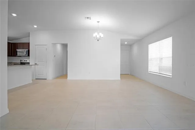 an empty room with kitchen and windows