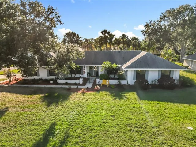 a front view of a house with swimming pool next to a big yard