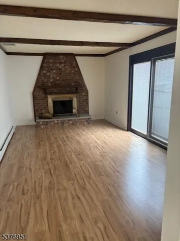 a view of a livingroom with wooden floor and a fireplace