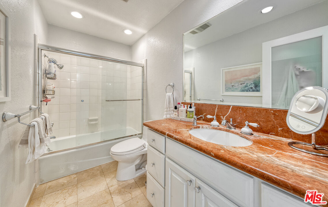 4350 Vía Dolce, Unit 105 Marina del Rey, CA 90292 - Photo 17 of 31 a bathroom with a granite countertop sink a toilet a mirror and shower