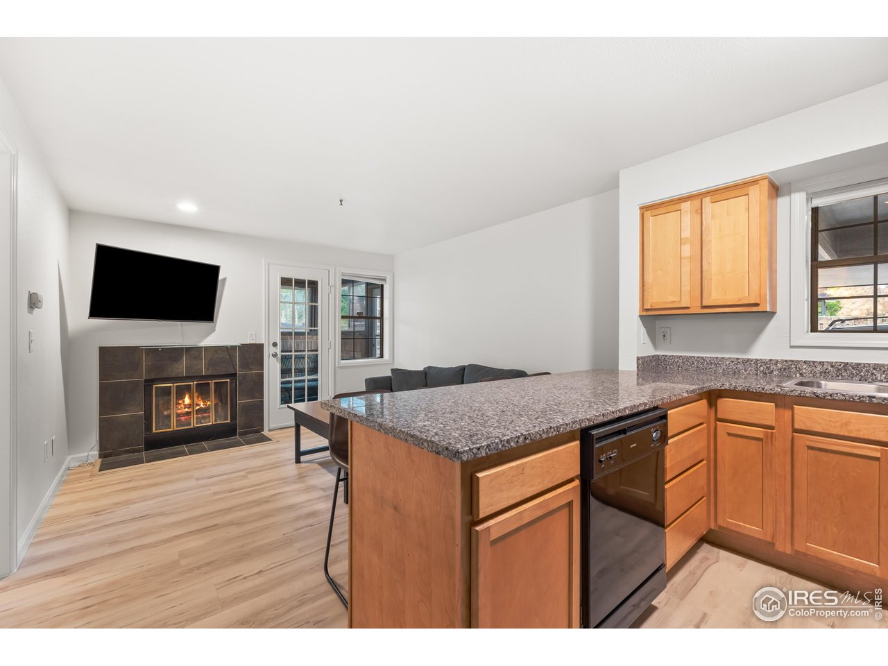 1405 Broadway, Unit 101 Boulder, CO 80302 - Photo 5 of 22 a kitchen with granite countertop a stove top oven a sink dishwasher and a fireplace with wooden floor