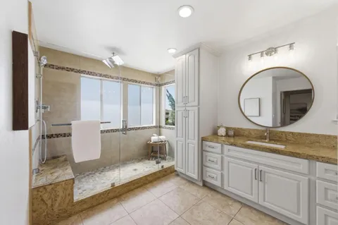a spacious bathroom with a granite countertop sink mirror and a bathtub
