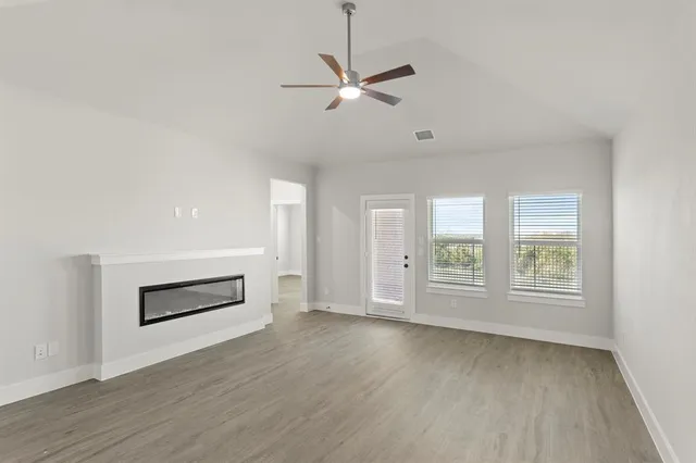 an empty room with windows and ceiling fan