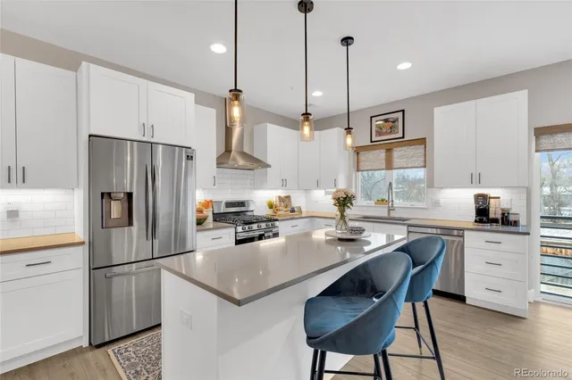 a kitchen with a refrigerator a stove a sink and white cabinets