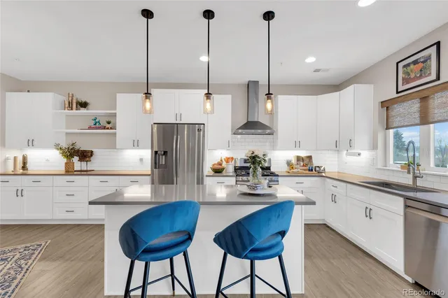 a kitchen with stainless steel appliances kitchen island a refrigerator and white cabinets