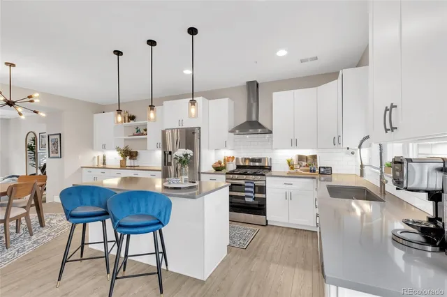 a kitchen with stainless steel appliances kitchen island granite countertop a stove a sink and white cabinets