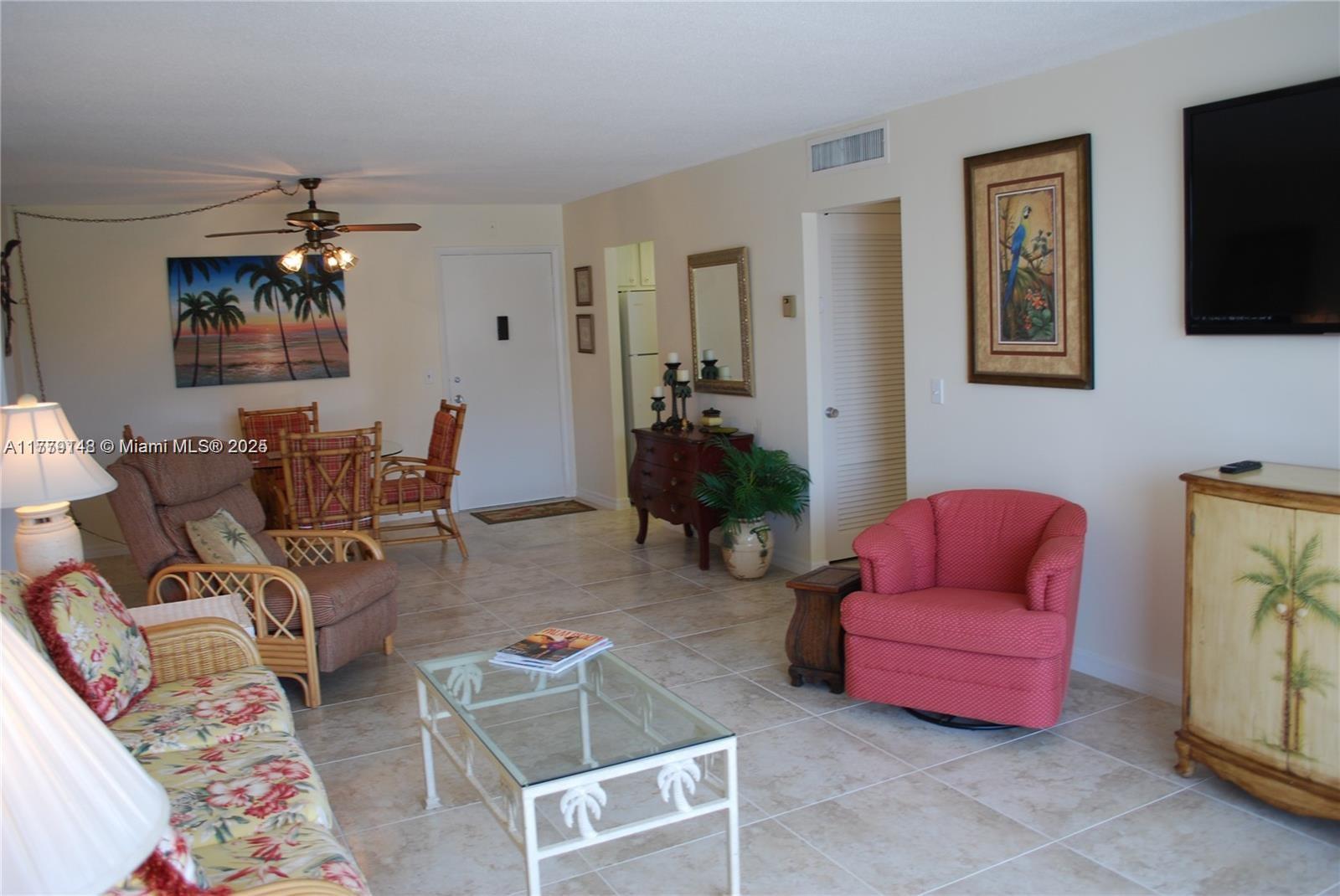 125 South Ocean Avenue, Unit 214 Palm Beach Shores, FL 33404 - Photo 9 of 26 a living room with furniture a flat screen tv and paintings on the wall