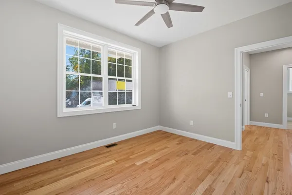 a view of empty room with wooden floor and fan