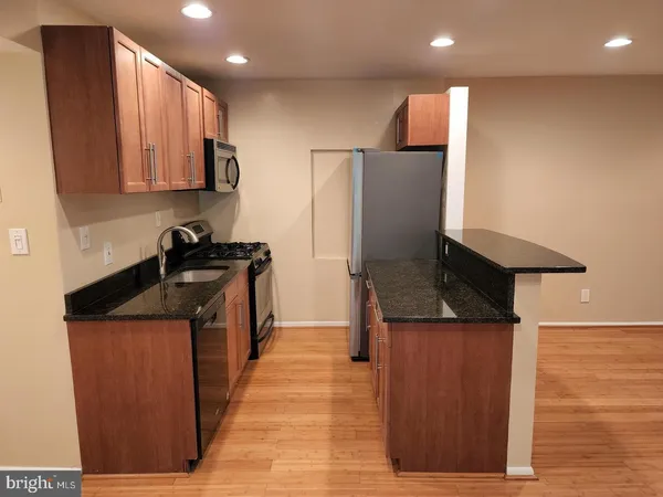 a kitchen with stainless steel appliances granite countertop a refrigerator a sink and a stove
