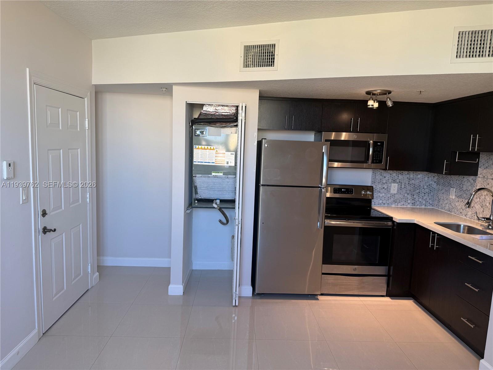2630 Southwest 28th Street, Unit 47 Miami, FL 33133 - Photo 2 of 7 a kitchen with stainless steel appliances a refrigerator and a sink