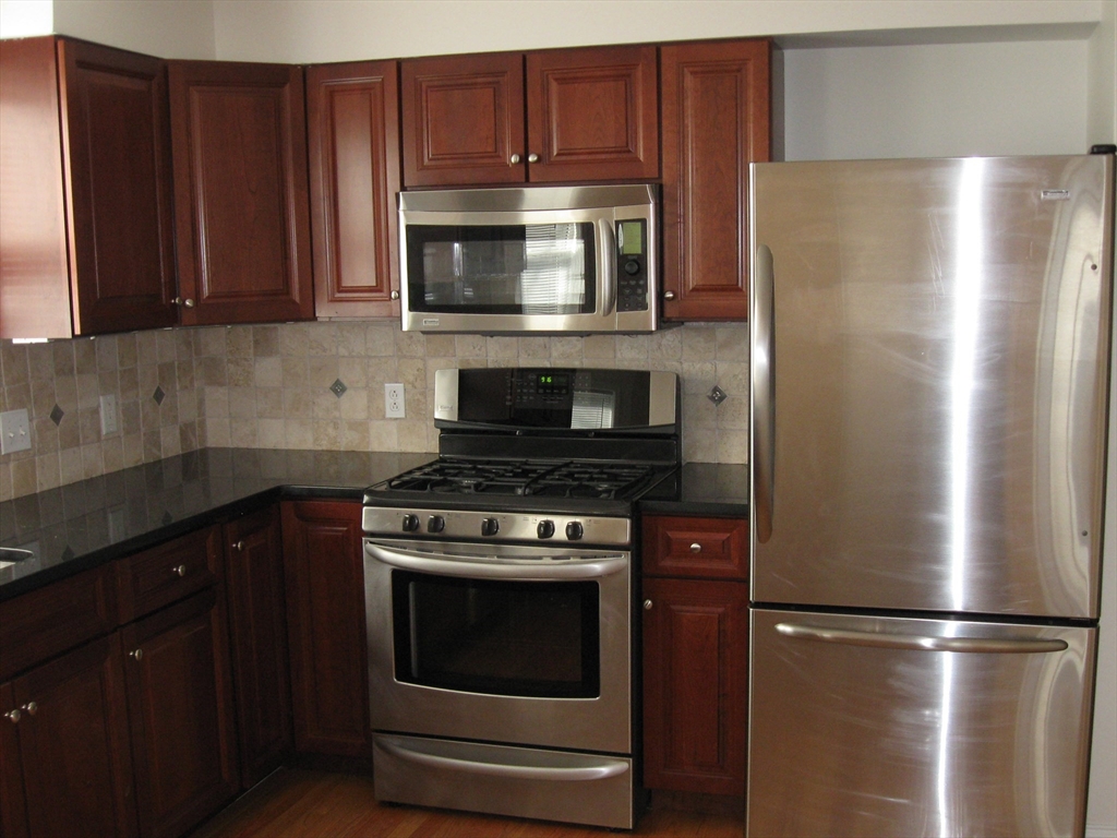 2856 Washington Street Boston, MA 02119 - Photo 30 of 39 a kitchen with stainless steel appliances granite countertop a refrigerator stove and microwave