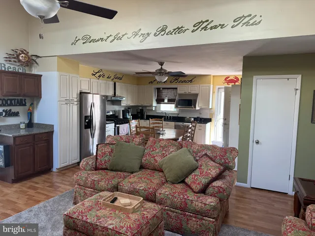 a living room with stainless steel appliances furniture and a kitchen view